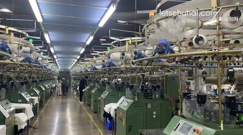 开工,各色面料整齐码在货架上,这里生产的是需要人工缝制的有缝产品